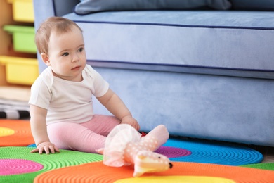 Cute baby sitting on floor in living room