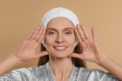 Woman massaging her face on beige background