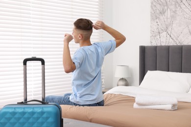 Guest stretching on bed in stylish hotel room