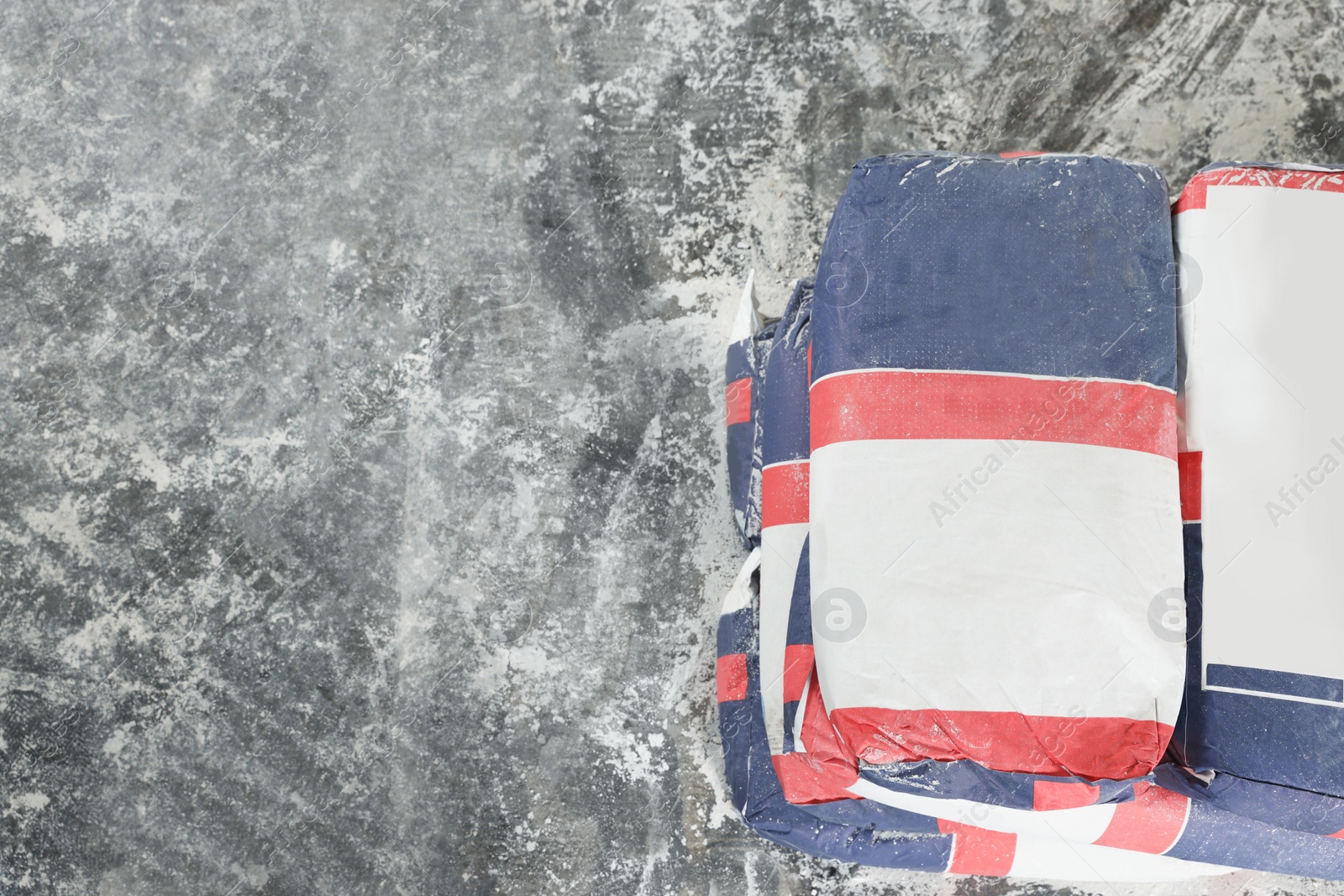 Photo of Cement powder in bags on stone floor, top view. Space for text