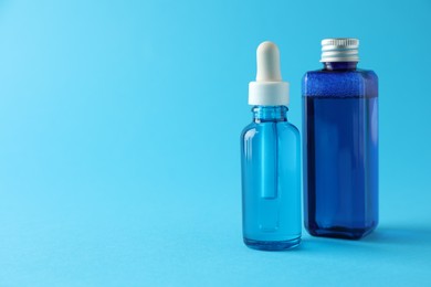 Photo of Bottles of cosmetic products on light blue background. Space for text