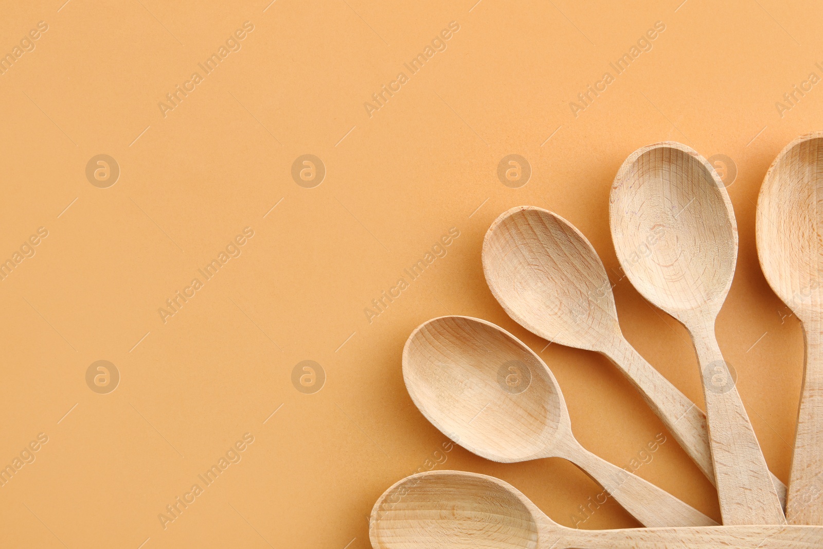 Photo of Flat lay composition with clean wooden spoons and space for text on color background