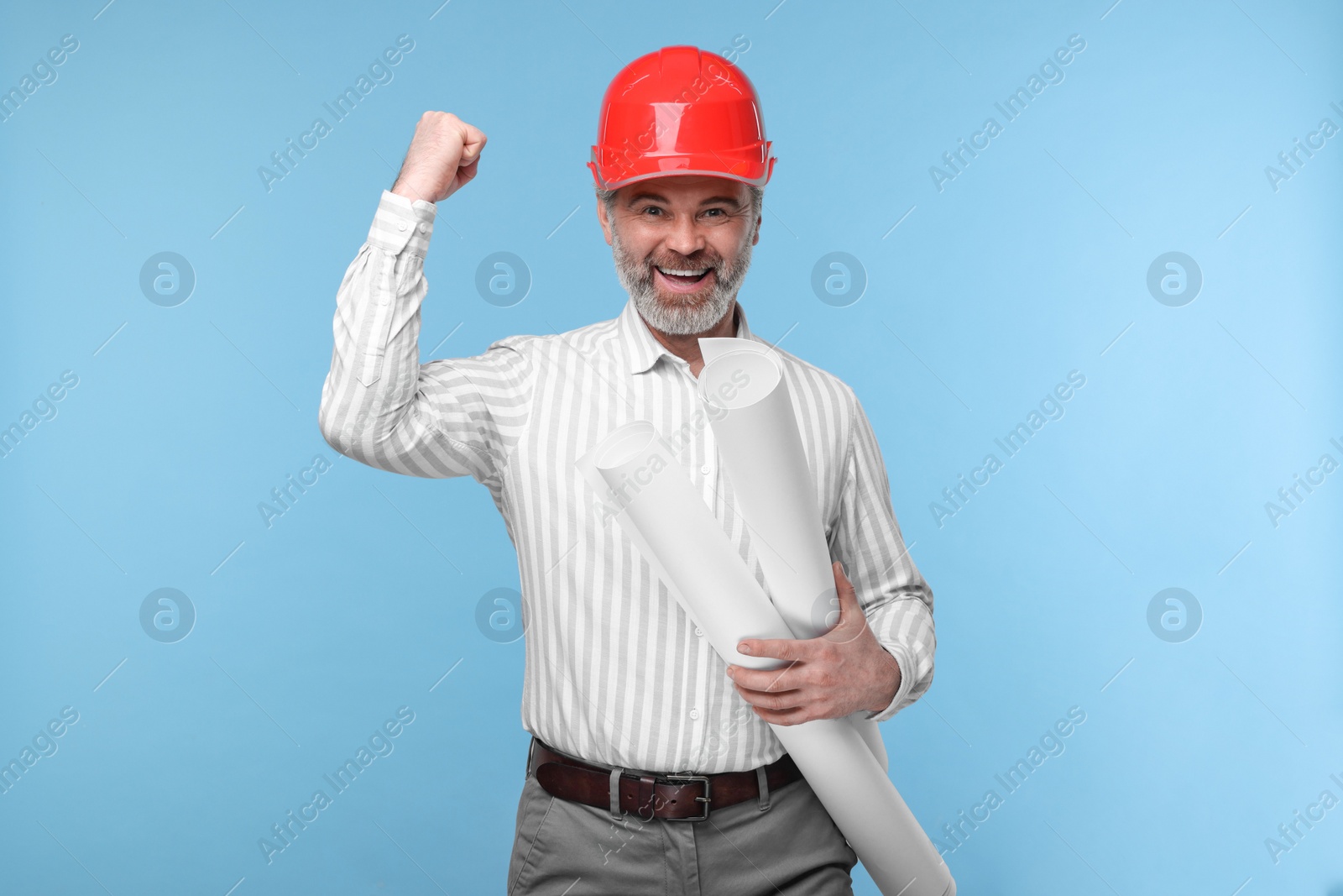 Photo of Architect in hard hat holding drafts on light blue background