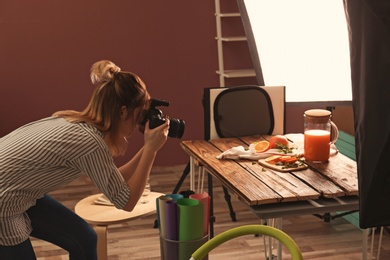 Photo of Woman taking picture of oranges and jug with juice on table. Food photography