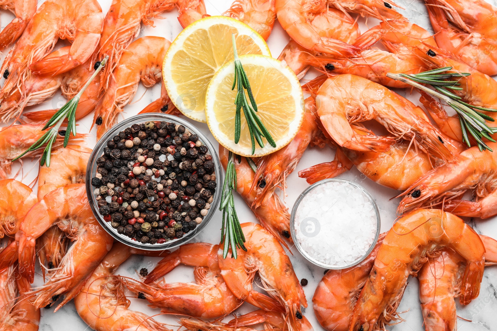 Photo of Delicious cooked shrimps with lemon and spices on white marble table, flat lay