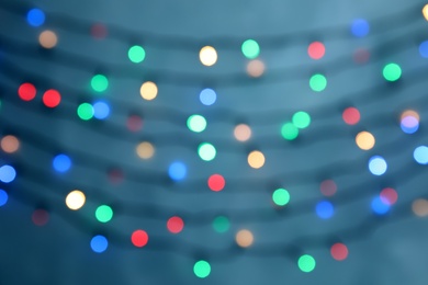 Blurred view of Christmas lights on color background