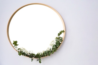 Photo of New round mirror in wooden frame on white wall, space for text. Idea for interior design