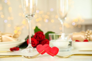 Photo of Golden forks with red hearts on white table. Romantic dinner