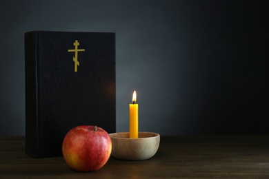 Photo of Bible, candle and apple on wooden table, space for text. Lent season