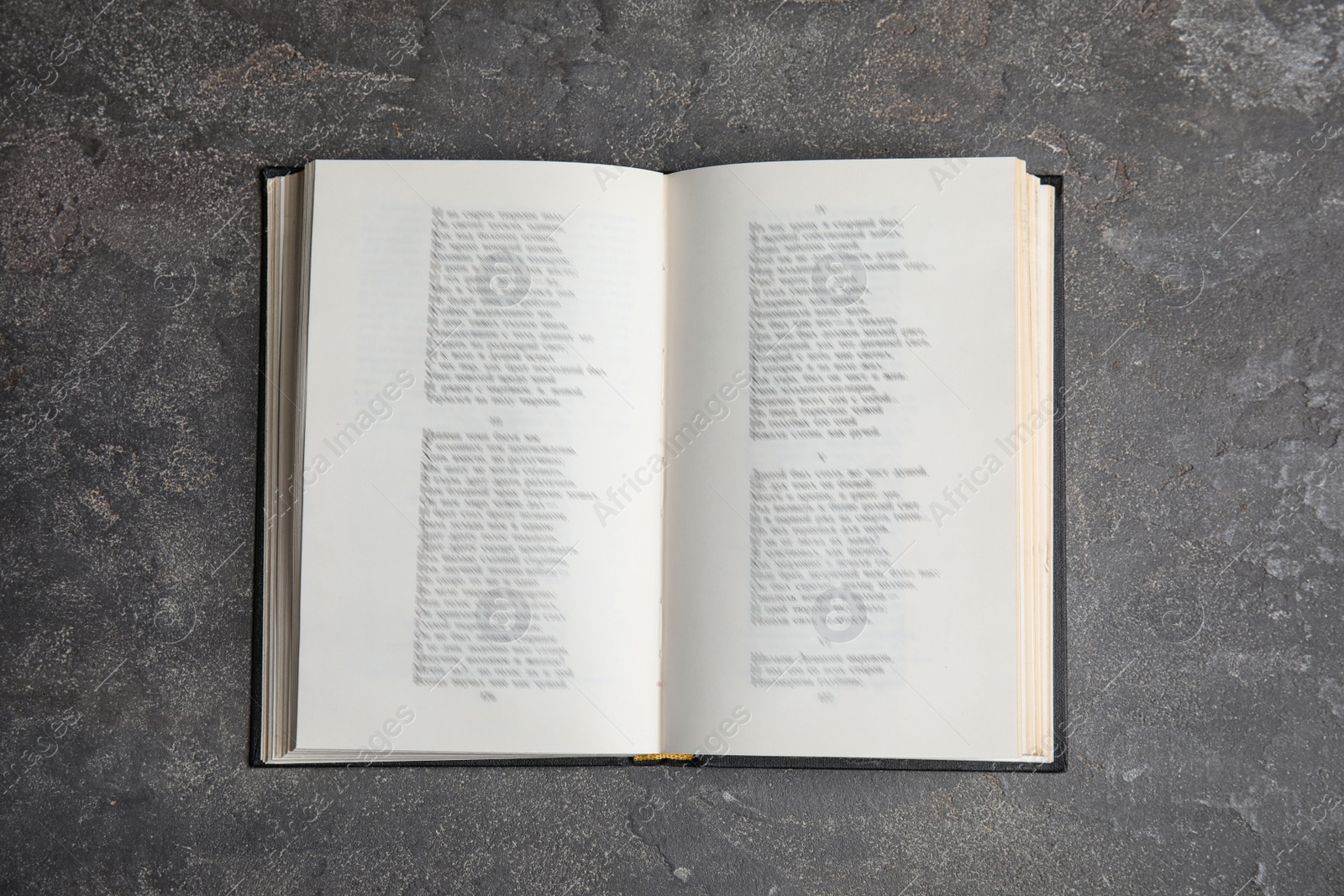 Photo of Open book on grey stone table, top view