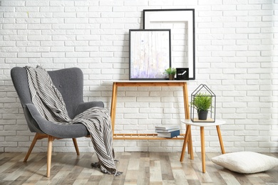 Photo of Stylish living room interior with comfortable armchair near brick wall