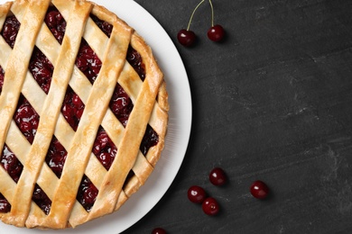 Photo of Delicious fresh pie and cherries on black slate table, flat lay. Space for text