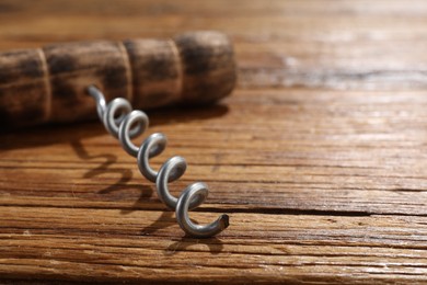 Photo of One corkscrew on wooden table, closeup. Space for text