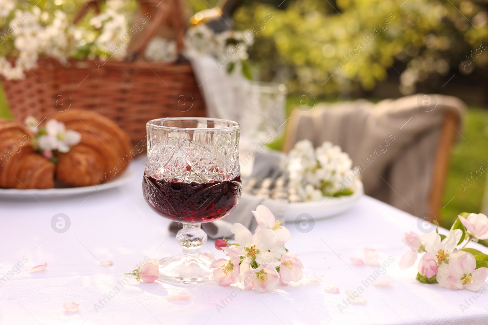 Photo of Stylish table setting with beautiful spring flowers, wine and croissants in garden