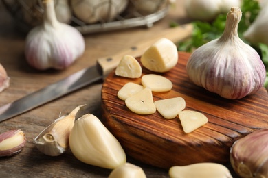 Photo of Fresh sliced and whole garlic on wooden table, closeup. Organic product