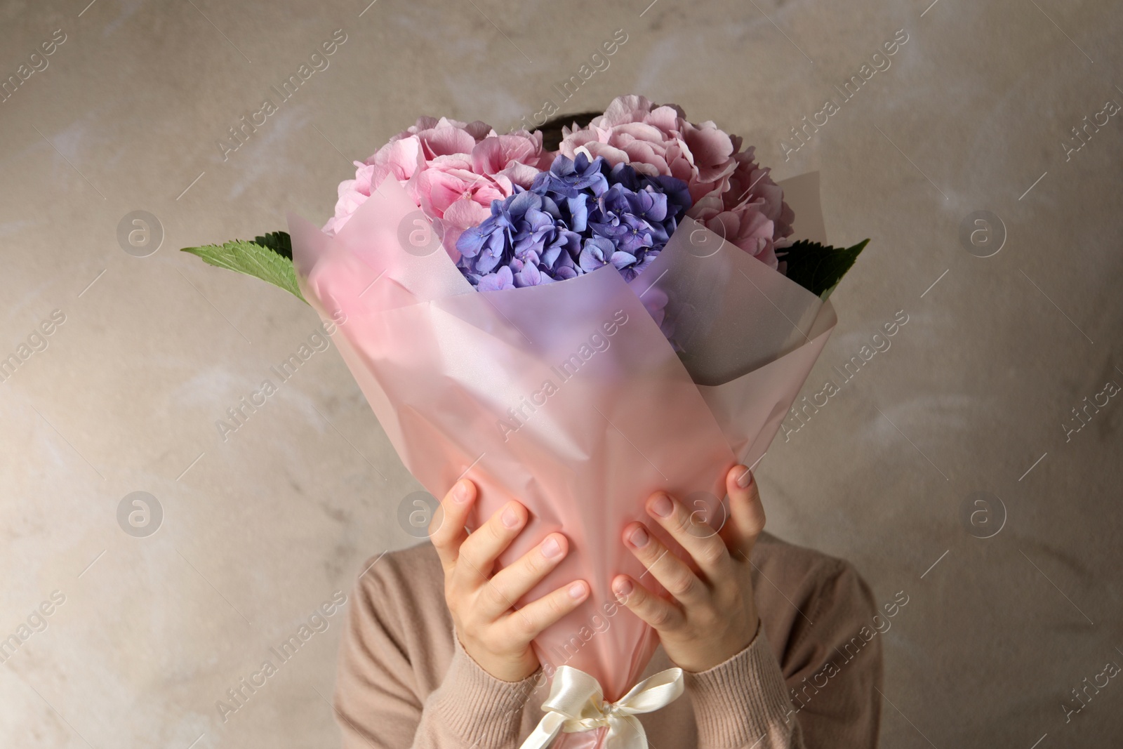 Photo of Woman with bouquet of beautiful hortensia flowers on beige background