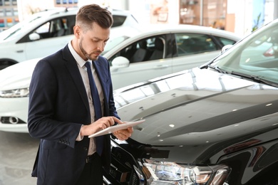 Photo of Salesman with tablet in salon. Buying new car