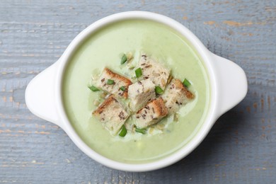 Delicious asparagus soup with croutons on grey wooden table, top view