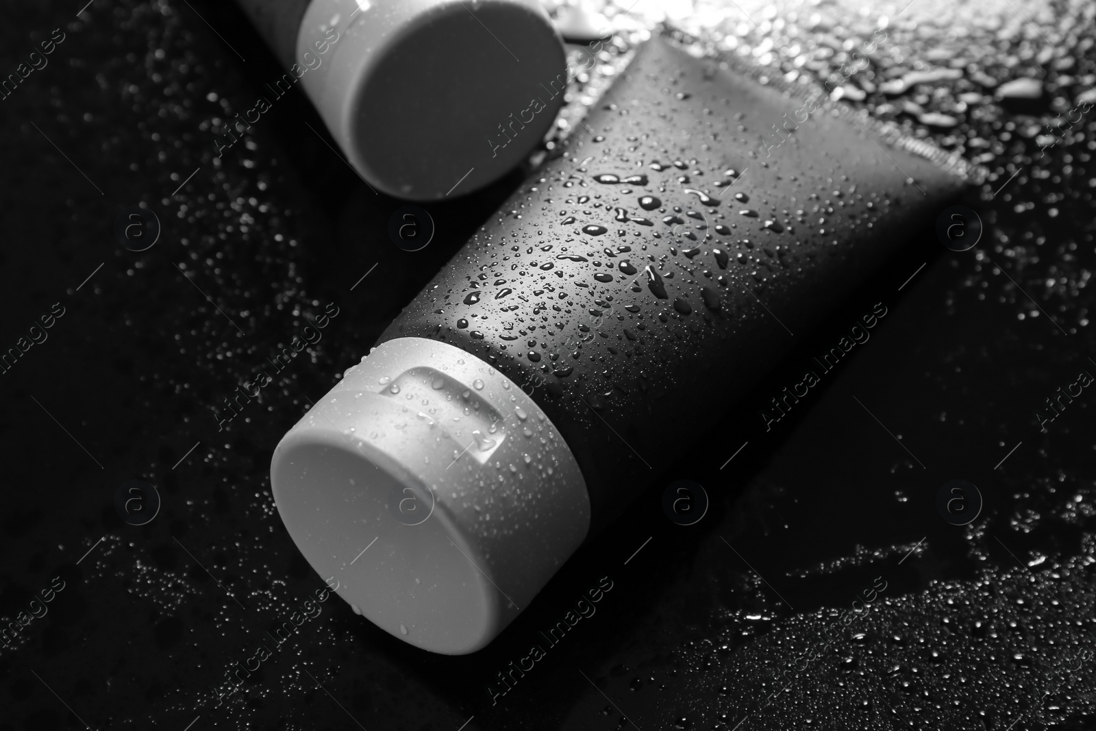 Photo of Tube on wet black surface, space for design. Men's cosmetic product