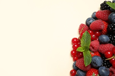 Mix of different fresh berries and mint on light background, flat lay. Space for text