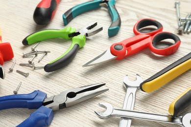 Photo of Different pliers, scissors and other tools for repair on wooden table, closeup
