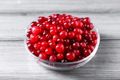 Photo of Fresh ripe cranberries in bowl on grey wooden table, closeup