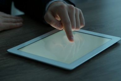 Man using tablet at wooden table, closeup