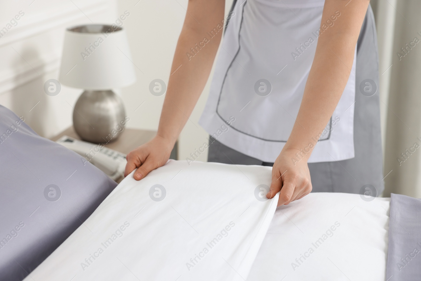 Photo of Maid making bed in hotel room, closeup