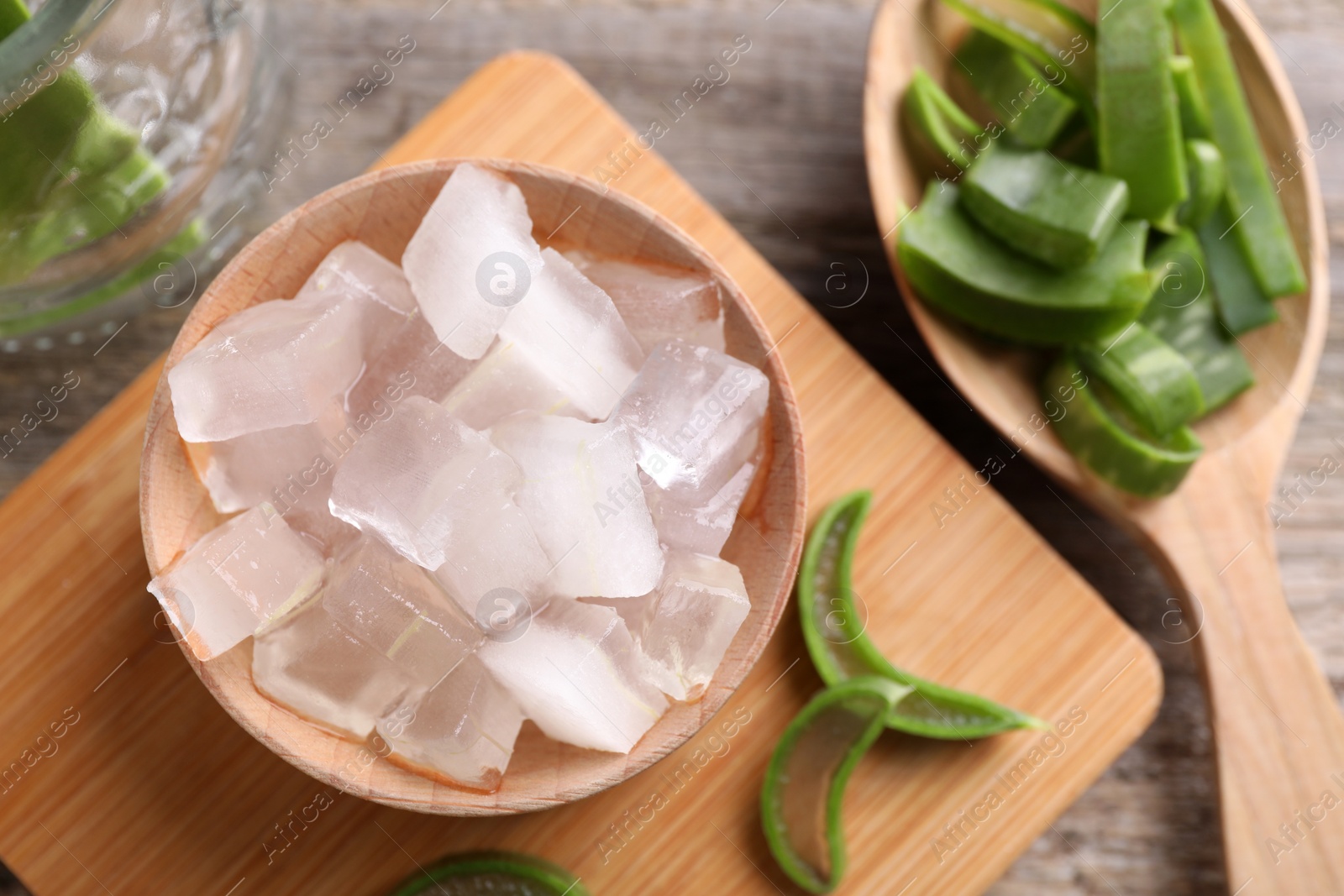 Photo of Aloe vera gel and slices of plant on wooden table, flat lay