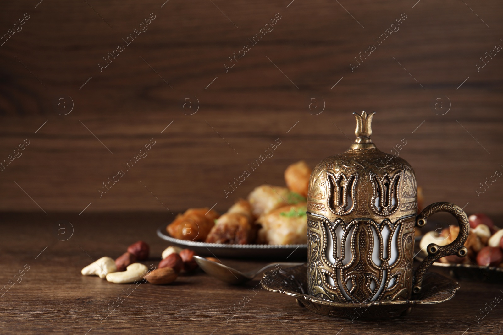 Photo of Beautiful vintage cup holder, nuts and baklava dessert on wooden table, space for text