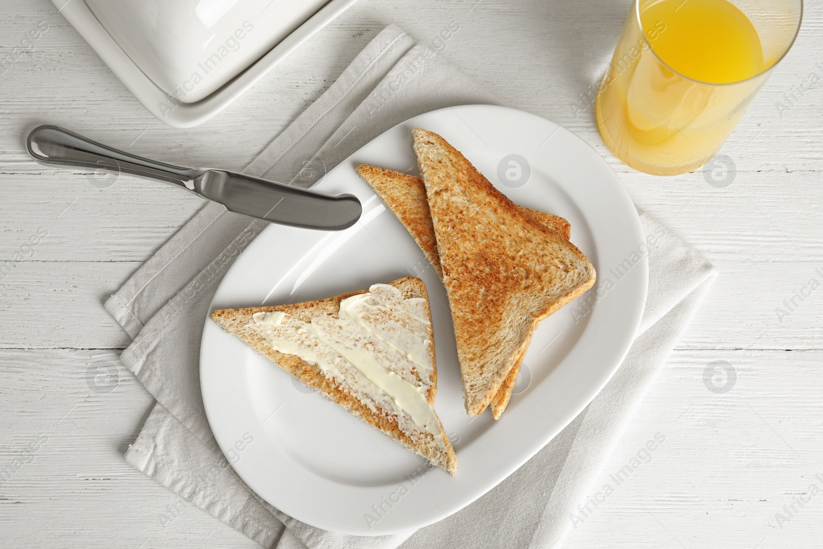 Photo of Tasty bread with butter served for breakfast on white wooden table, top view