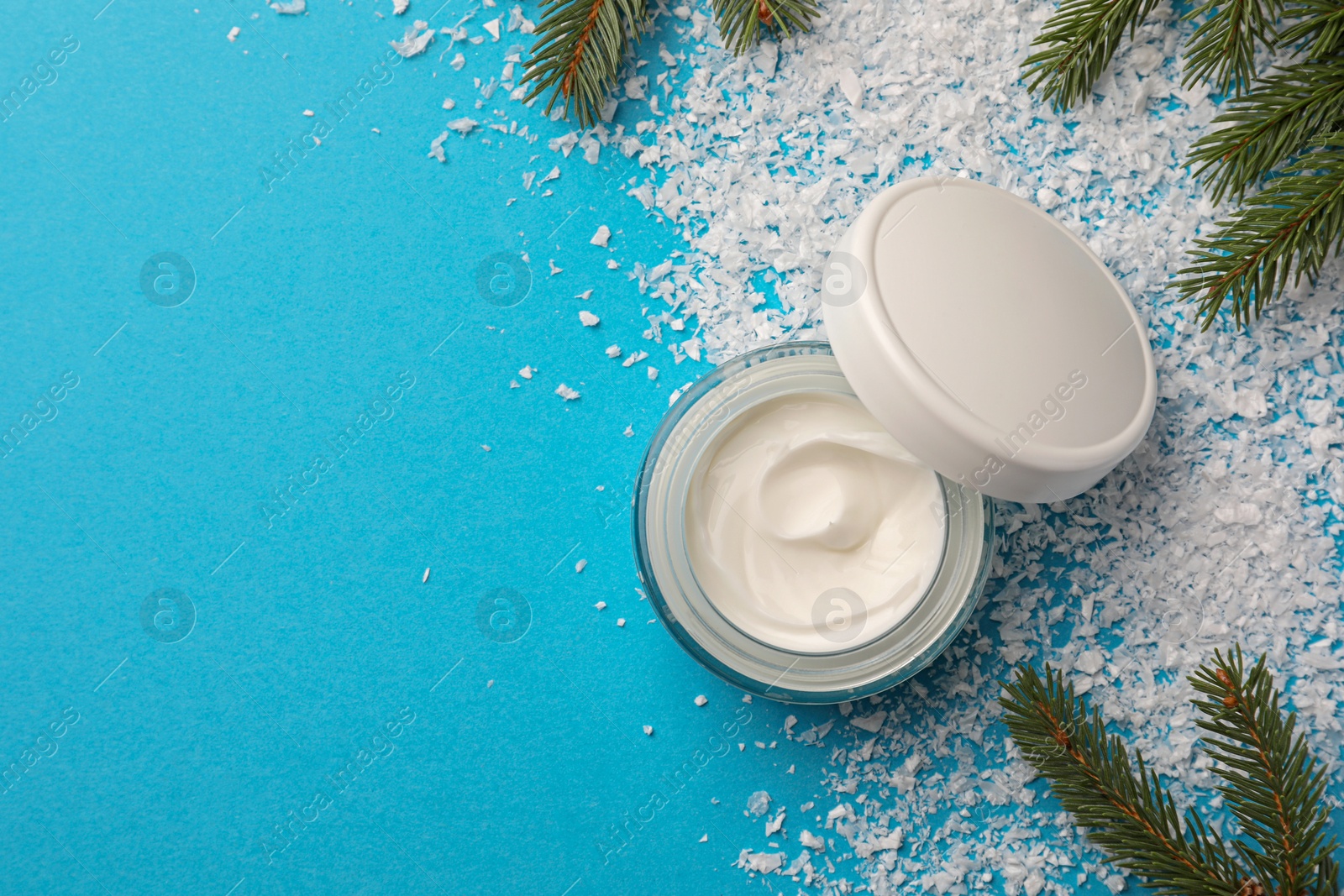 Photo of Jar of hand cream and Christmas decor on light blue background, flat lay with space for text. Winter skin care