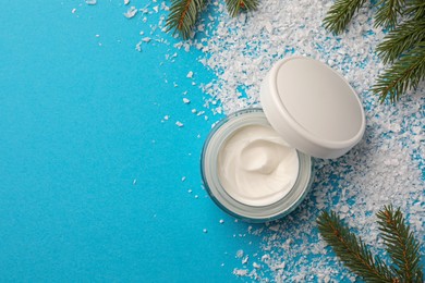 Photo of Jar of hand cream and Christmas decor on light blue background, flat lay with space for text. Winter skin care