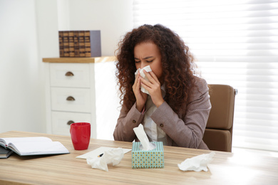 Photo of Sick African-American woman at workplace. Influenza virus