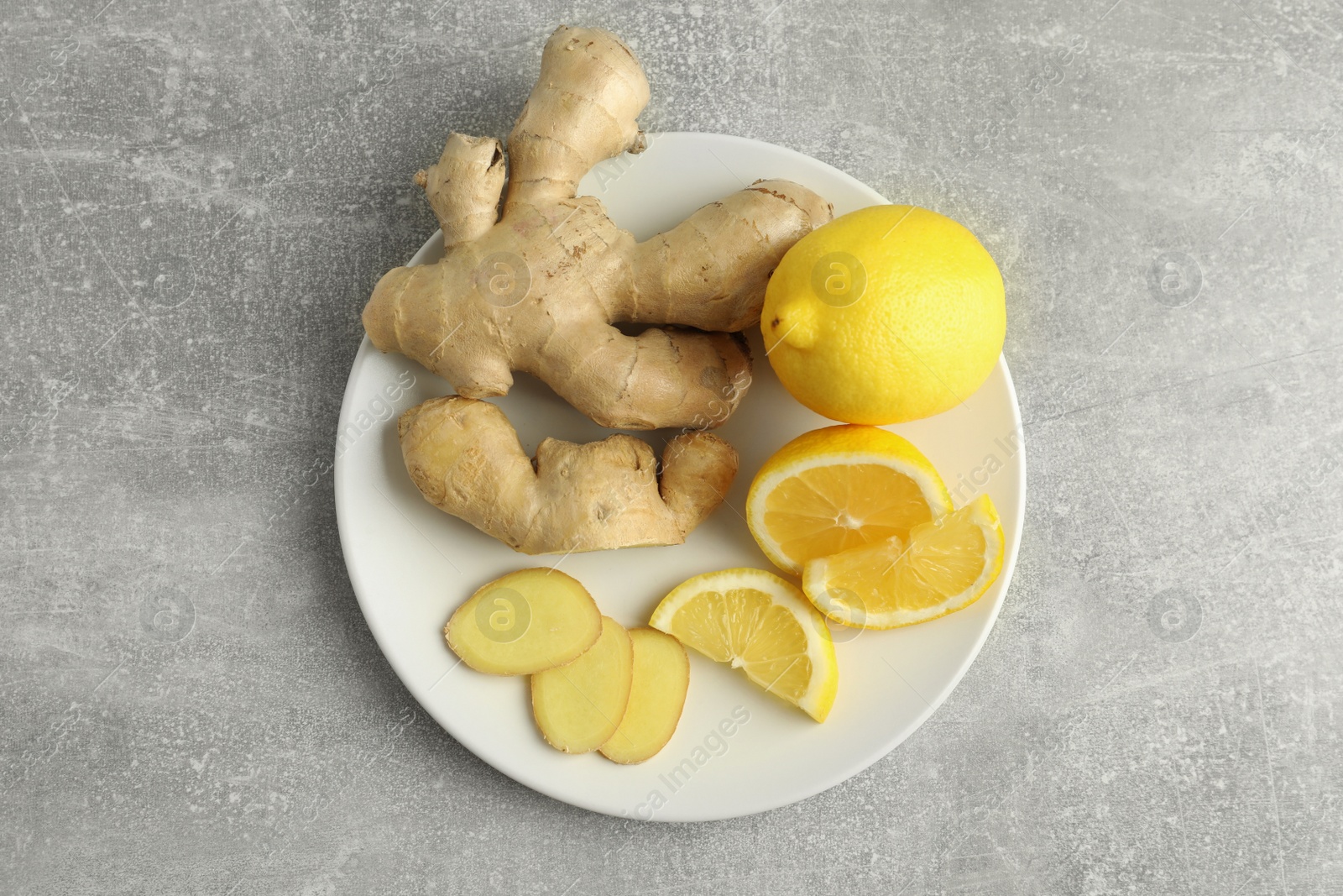 Photo of Fresh lemons and ginger on grey table, top view