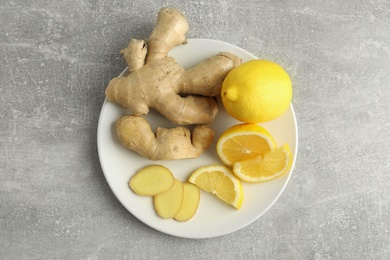 Photo of Fresh lemons and ginger on grey table, top view