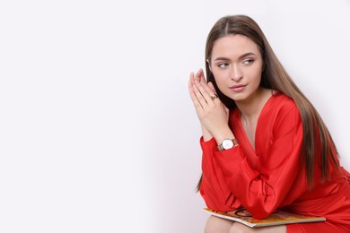 Photo of Young woman with fashion magazine near white wall, space for text