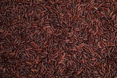Photo of Heap of red rice as background, top view. Veggie seeds