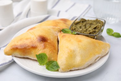 Photo of Delicious samosas with basil and pesto sauce on white table, closeup