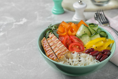 Photo of Tasty rice with beans and chicken meat on light grey marble table