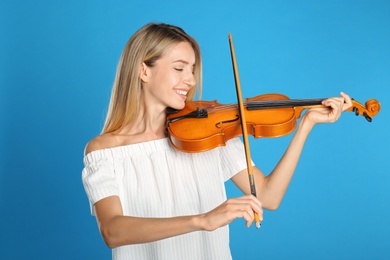 Photo of Beautiful woman playing violin on blue background