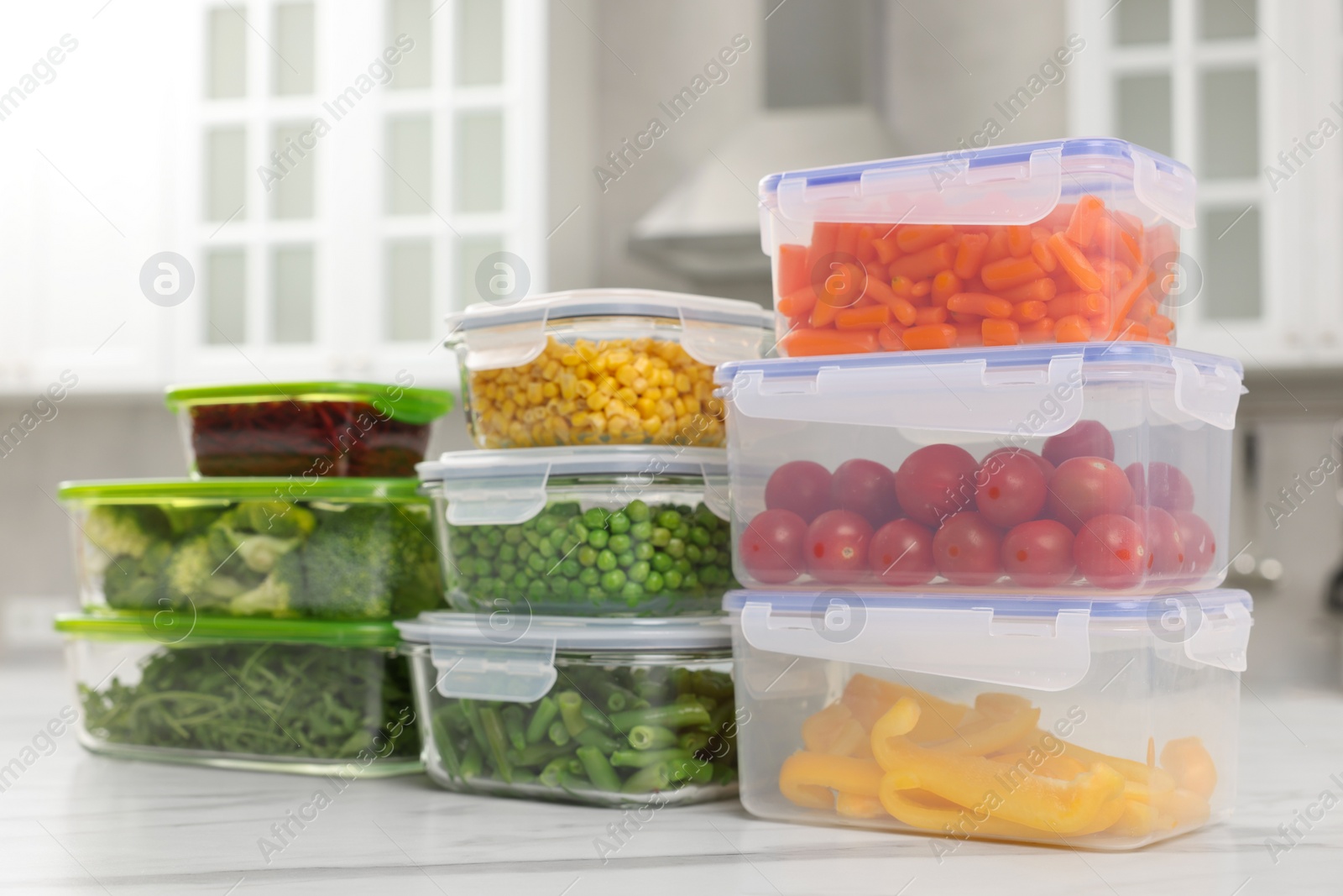 Photo of Glass and plastic containers with different fresh products on white marble table in kitchen. Food storage