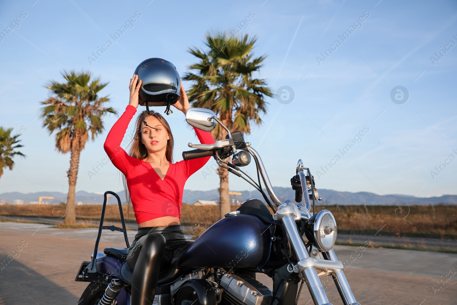 Photo of Beautiful young woman with helmet sitting on motorcycle outdoors