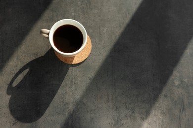 Photo of Cup of delicious coffee on grey table, top view. Space for text