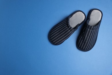 Photo of Pair of stylish slippers on blue background, top view. Space for text