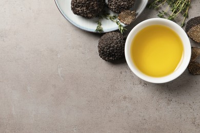 Photo of Fresh truffles, oil in bowl and thyme on light grey table, flat lay. Space for text