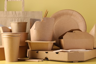 Eco friendly food packaging. Paper containers, tableware and bag on pale yellow background