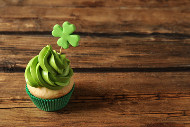 Photo of Delicious decorated cupcake on wooden table, space for text. St. Patrick's Day celebration