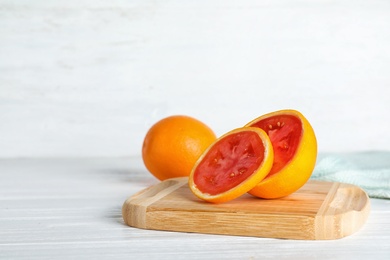 Photo of Wooden board with sliced orange revealing tomato inside on table. Think differently