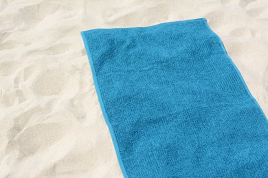 Photo of Beautiful soft blue towel on sandy beach